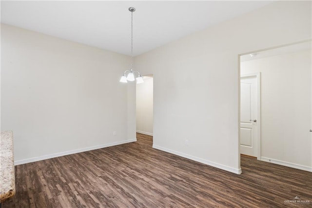 spare room with a chandelier and dark hardwood / wood-style flooring