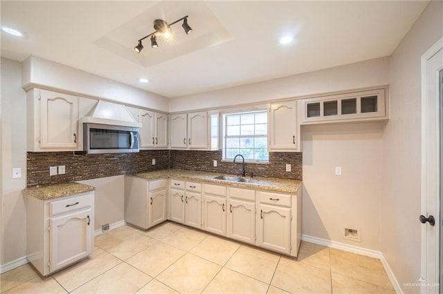 kitchen featuring backsplash, a tray ceiling, white cabinetry, and sink