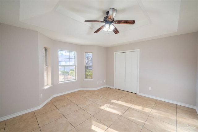 unfurnished bedroom with a raised ceiling, ceiling fan, and light tile patterned floors