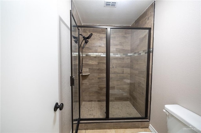 bathroom with tile patterned floors, toilet, and walk in shower