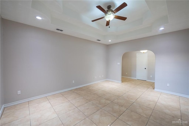 tiled spare room with ceiling fan and a tray ceiling