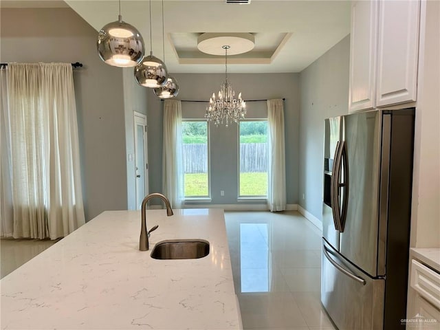 2301 Mcleod Ave, Edinburg, TX 78539 - kitchen featuring stainless steel fridge with ice dispenser, light stone countertops, white cabinetry, a chandelier, and decorative light fixtures