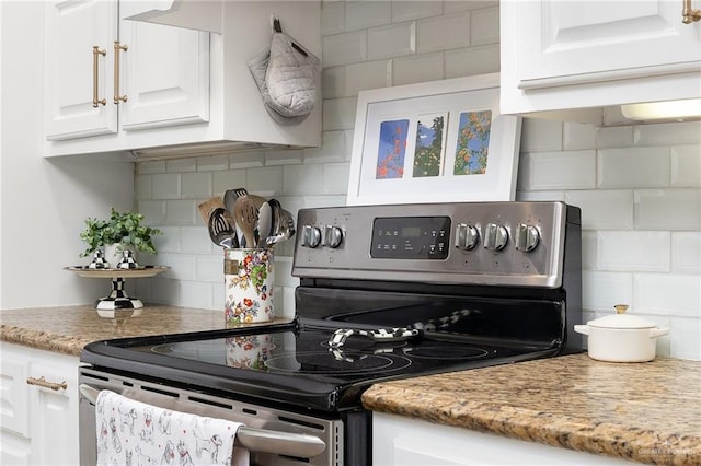 kitchen featuring stainless steel electric range, backsplash, white cabinets, and light stone countertops