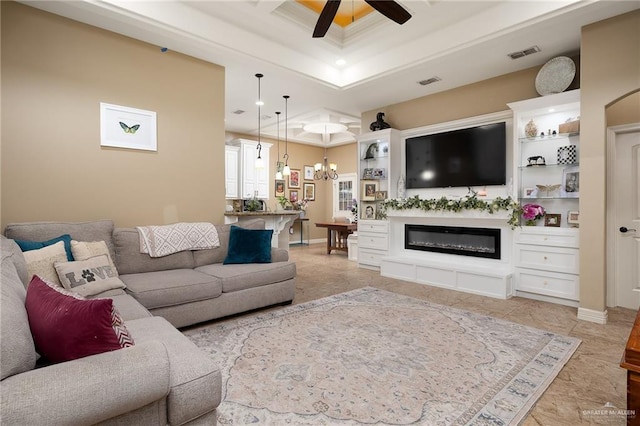 living room with ceiling fan with notable chandelier and ornamental molding