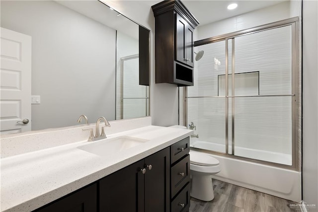 full bathroom with vanity, hardwood / wood-style floors, toilet, and combined bath / shower with glass door