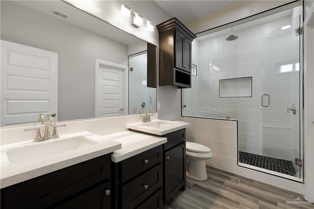 bathroom featuring hardwood / wood-style flooring, vanity, toilet, and a shower with door