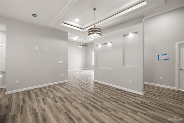 empty room featuring ceiling fan, a tray ceiling, and hardwood / wood-style floors