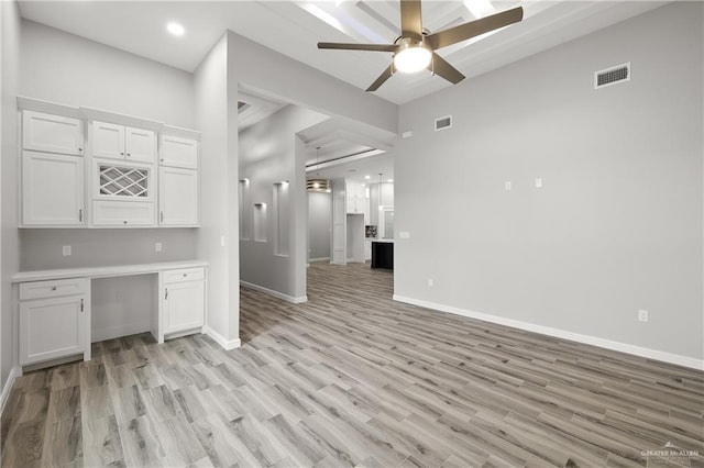 interior space featuring ceiling fan, built in desk, and light wood-type flooring