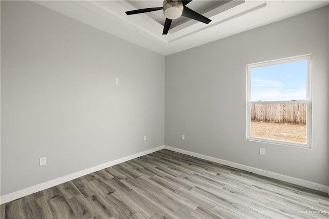 spare room featuring ceiling fan, a raised ceiling, and light wood-type flooring