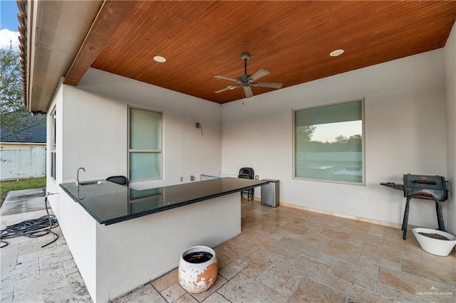 view of patio featuring ceiling fan and a bar