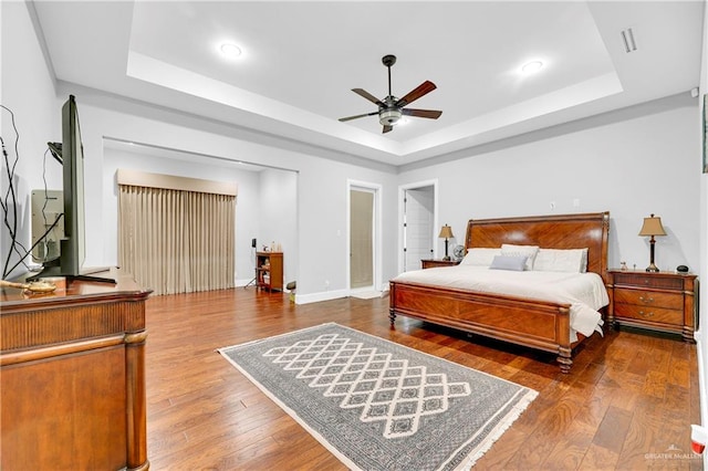 bedroom featuring hardwood / wood-style floors, ceiling fan, and a tray ceiling