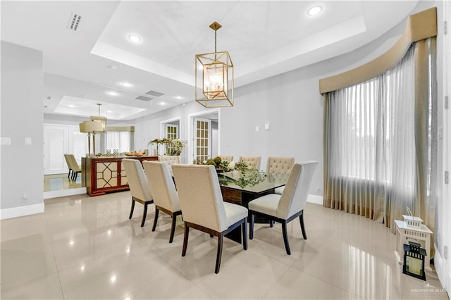 dining room with a chandelier, a raised ceiling, and light tile patterned flooring