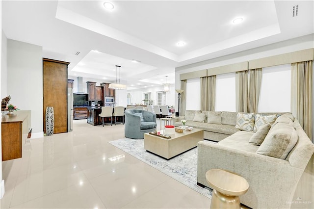 living room with a tray ceiling and light tile patterned floors