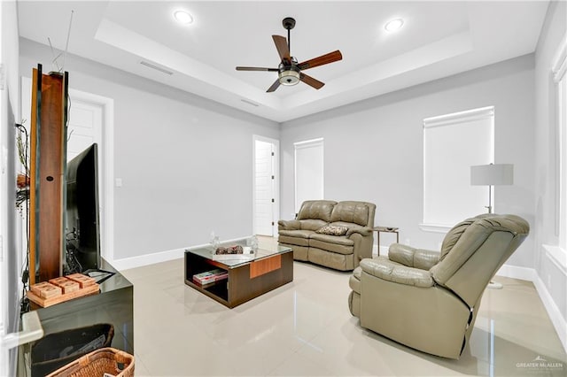 living room with a tray ceiling and ceiling fan