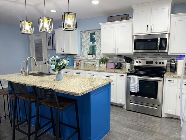 kitchen with white cabinetry, appliances with stainless steel finishes, and a center island with sink