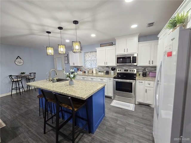 kitchen with sink, a breakfast bar area, white cabinets, a kitchen island with sink, and stainless steel appliances