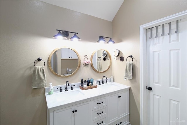 full bathroom featuring lofted ceiling, double vanity, and a sink