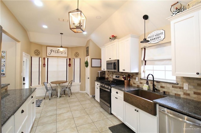 kitchen with stainless steel appliances, tasteful backsplash, a sink, and white cabinets