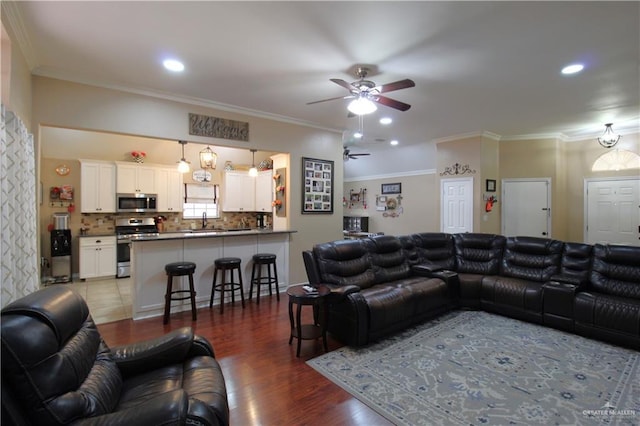 living room with a ceiling fan, ornamental molding, and wood finished floors