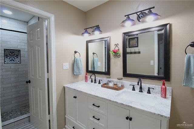 bathroom featuring a tile shower, double vanity, and a sink