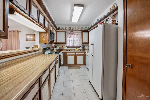 1009 Las Flores Dr, Alamo, TX 78516 - kitchen featuring white appliances, light tile patterned flooring, a textured ceiling, and a sink