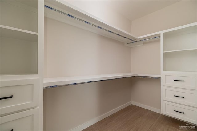 walk in closet featuring built in desk and light hardwood / wood-style flooring