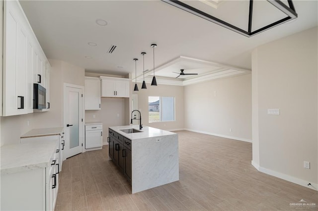 kitchen with sink, white cabinetry, a kitchen island with sink, pendant lighting, and light hardwood / wood-style floors