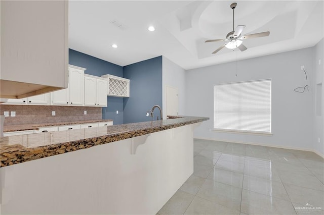 3313 Roadrunner Dr, Edinburg, TX 78541 - kitchen featuring stone countertops, decorative backsplash, white cabinets, a ceiling fan, and a raised ceiling