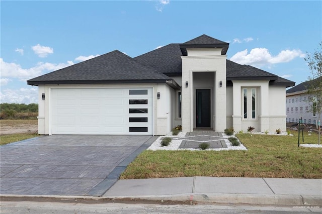 prairie-style house featuring a garage and a front lawn