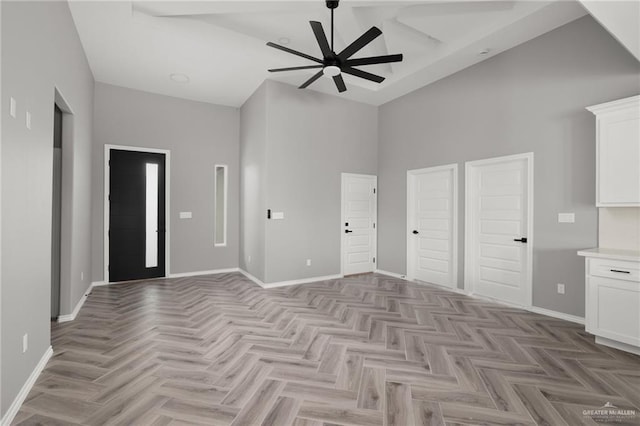 interior space with a towering ceiling, ceiling fan, and light parquet flooring