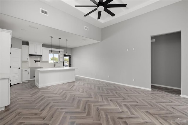 kitchen featuring a kitchen island, ceiling fan, decorative light fixtures, light parquet flooring, and white cabinetry