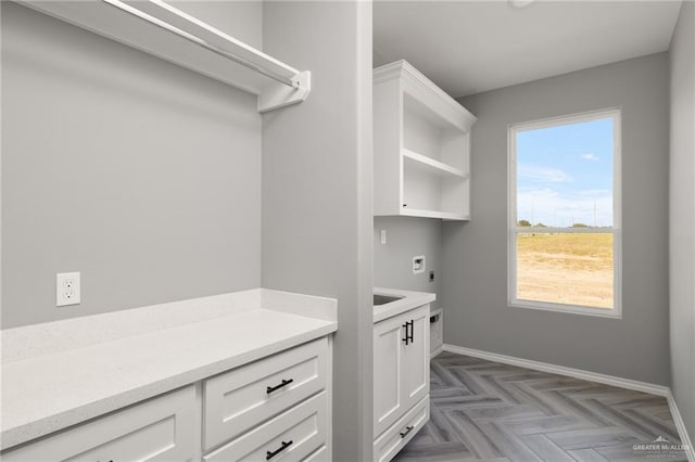 laundry room featuring hookup for an electric dryer, dark parquet flooring, and cabinets