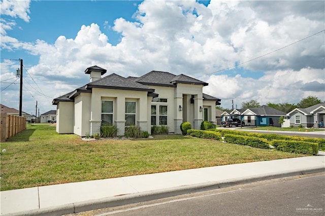 prairie-style house with stucco siding, a residential view, a front lawn, and fence