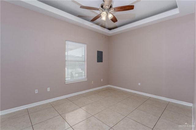 empty room with a raised ceiling, electric panel, and baseboards