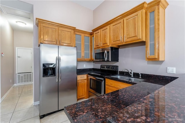 kitchen featuring light tile patterned floors, visible vents, brown cabinetry, stainless steel appliances, and a sink