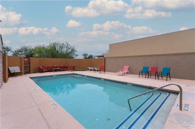 community pool with a patio area and fence