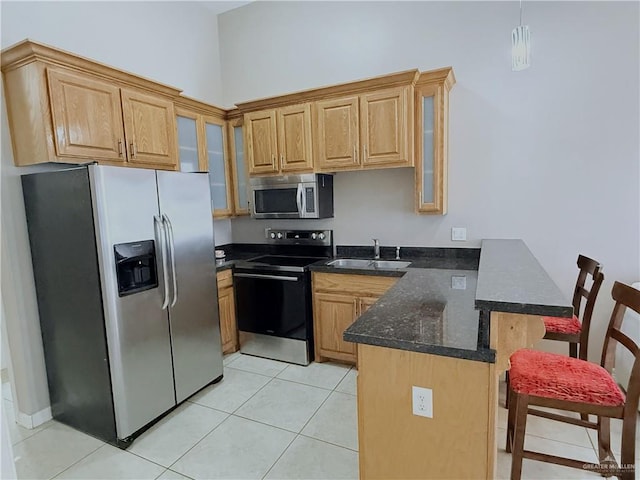 kitchen with light tile patterned flooring, stainless steel appliances, a breakfast bar, a peninsula, and a sink