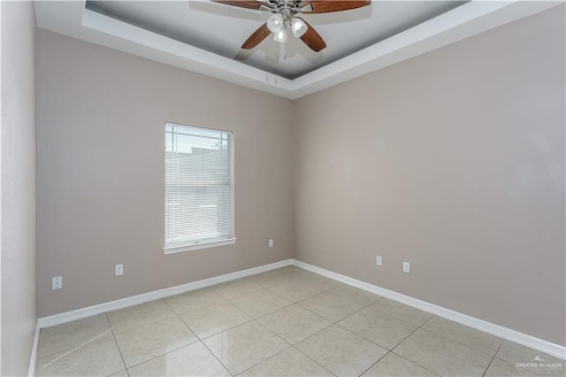 unfurnished room featuring light tile patterned floors, baseboards, a tray ceiling, and ceiling fan