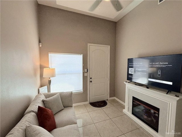 living area with light tile patterned floors, baseboards, and a ceiling fan