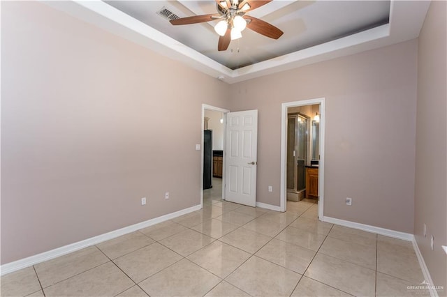 empty room featuring light tile patterned floors, baseboards, visible vents, a raised ceiling, and ceiling fan