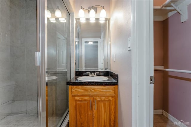 full bathroom with tile patterned flooring, baseboards, a shower stall, and vanity