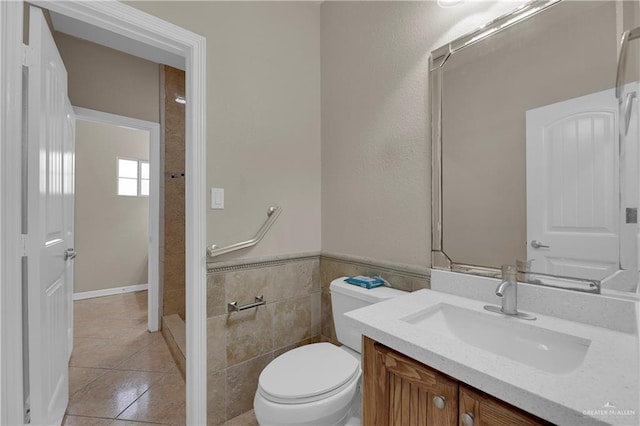 bathroom with tile patterned flooring, vanity, tile walls, and toilet