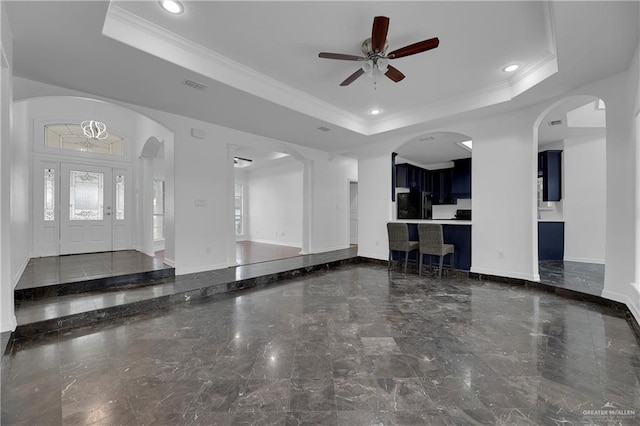 unfurnished living room featuring crown molding, ceiling fan, and a raised ceiling