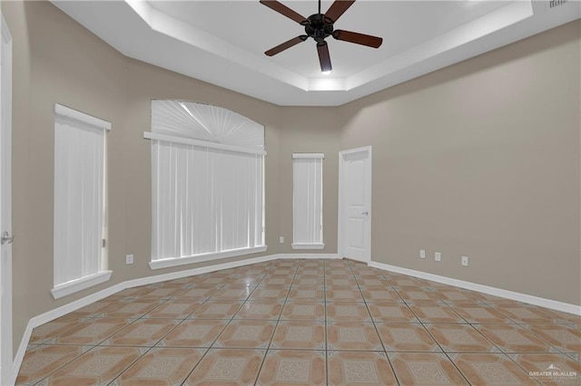 unfurnished room featuring light tile patterned floors, ceiling fan, and a tray ceiling