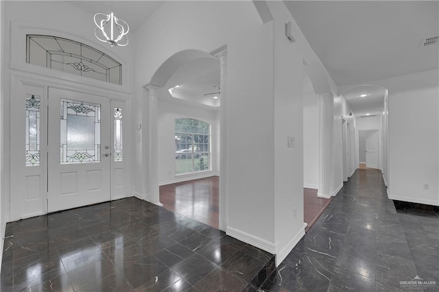 entryway featuring ornate columns, a high ceiling, and a chandelier