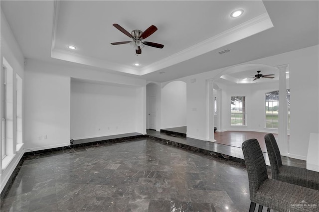 unfurnished living room with crown molding, a tray ceiling, and ceiling fan