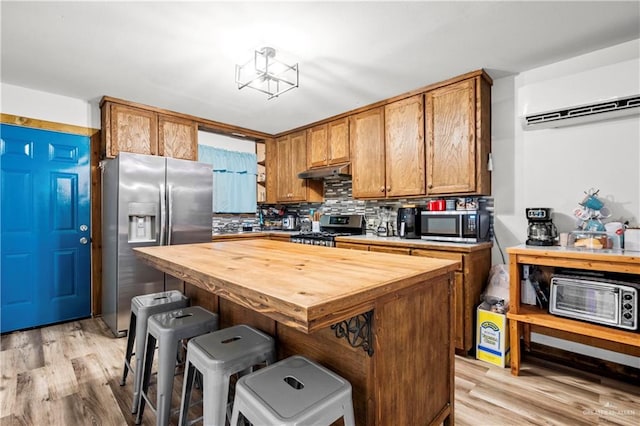 kitchen featuring wood counters, a breakfast bar area, a kitchen island, light hardwood / wood-style floors, and stainless steel appliances