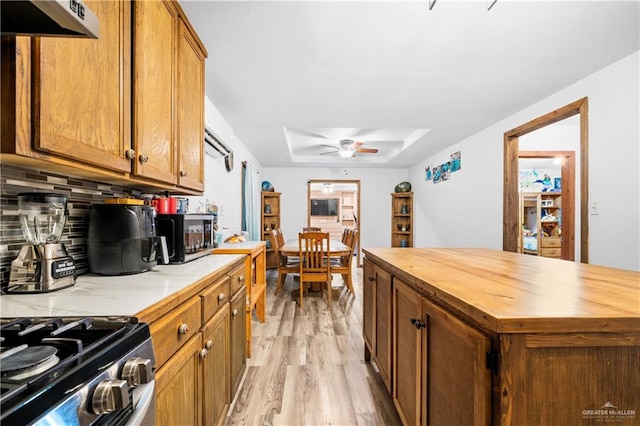 kitchen with decorative backsplash, wood counters, ceiling fan, a center island, and light hardwood / wood-style floors