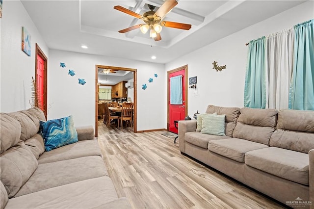 living room featuring a raised ceiling, ceiling fan, and light hardwood / wood-style floors