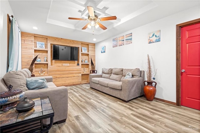 living room with hardwood / wood-style flooring, ceiling fan, and a tray ceiling